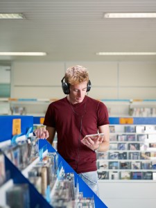 Man with headphone in music shop looking at cds and dvdsImpulse-based selling: a daily routine for packaged media and a challenge for online retailers?