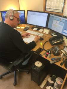 Office setting with multiple computer screens,man with headset speaking to customer