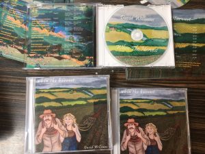 closed cd and an open cd case cd with countryside fields and a farmer and his wife