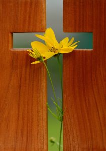 greean easter cross with yellow flowers placed across it