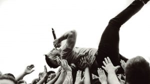 music festival singer being held up by crowds hands 