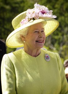 queen elizabeth II smiling in lemon outfit with hat